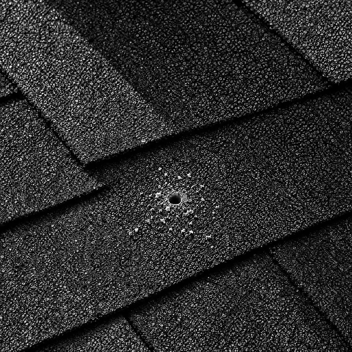 A bare asphalt-shingle roof with one pilot hole.