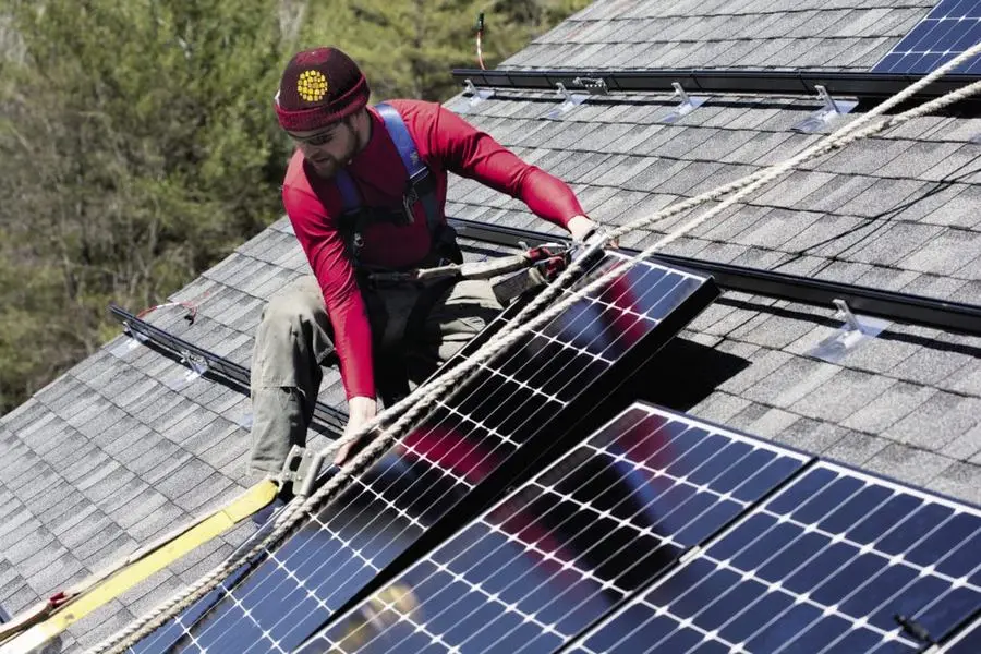 Installer mounting solar panels on a shingle roof